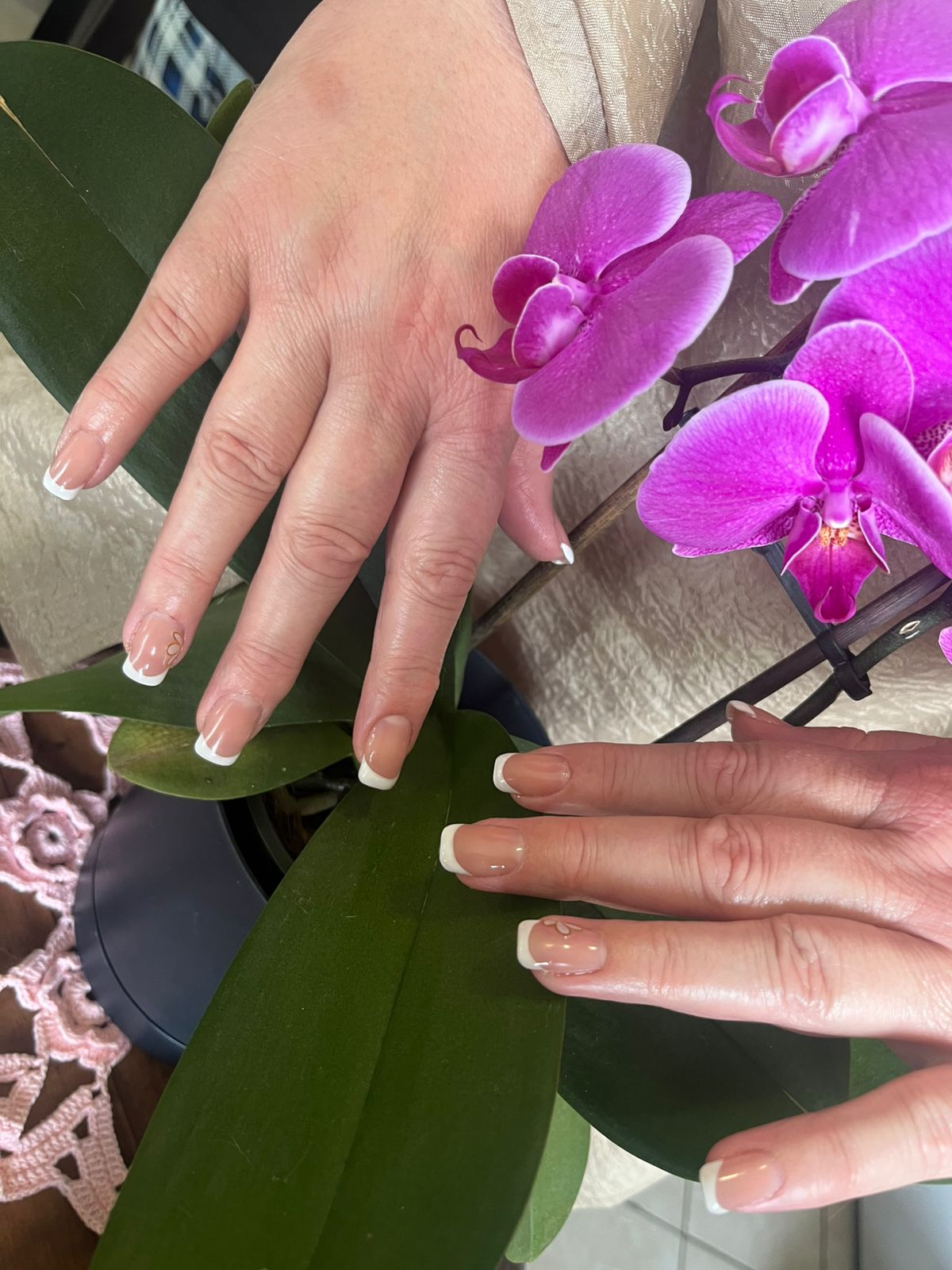 French nails beside purple orchids
